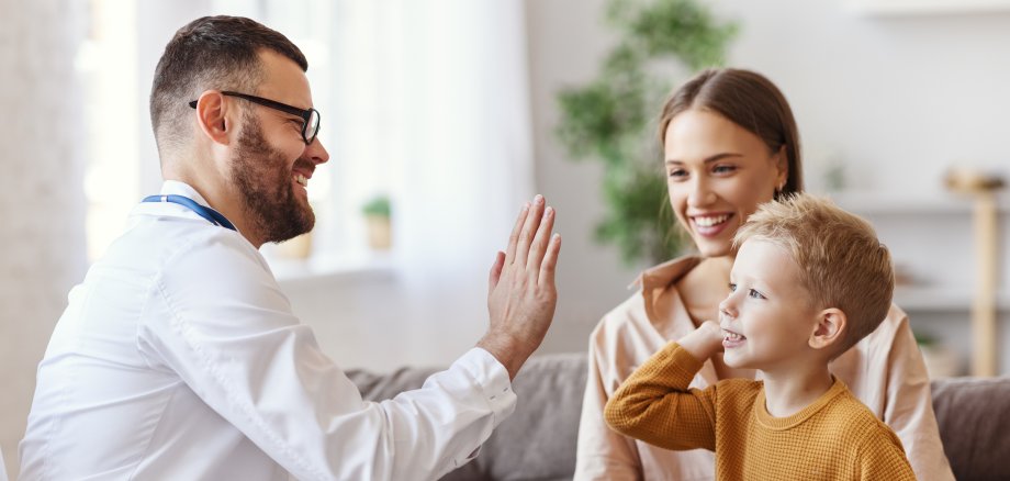 family doctor pediatrician conducts examination of child boy and giving high five to him 
